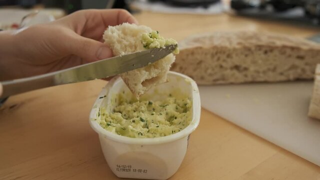 Typical Madeiran sweet potato bread bolo do caco spread with butter and parsley. Handheld shot
