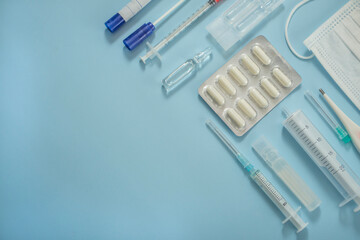 Obraz premium View from above. medical supplies, mask, syringe, ampoule with medicine or vaccine, thermometer, pills. Flat medical view place for text