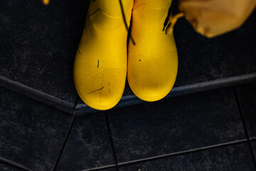 A pair of yellow rubber boots outside after rain on a gray background