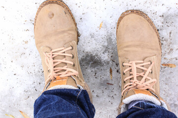 Feet shod in winter boots stand on the ice. Hiking shoes and winter activities.