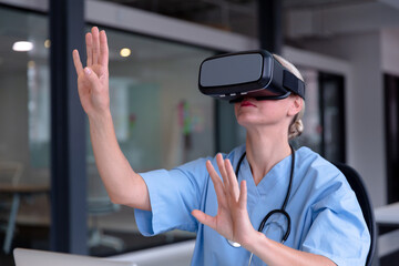 Caucasian female doctor wearing scrubs using vr headset and virtual interface