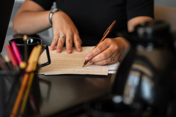 detail of black business woman signing document at meeting..