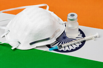  India flag, n95 face mask, needle syringe and vial. Concept of Covid-19 coronavirus vaccine distribution, supply shortage and healthcare crisis