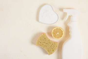 spray bottle, sponge, lemon and soda on beige backgrund top vire copy space