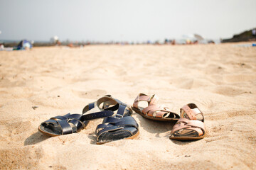 Two pairs of children's sandals lying on the beach