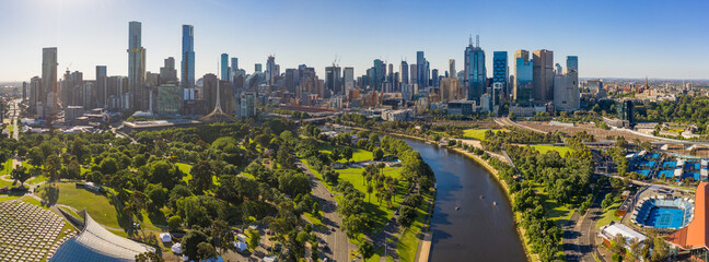 Aerial view of a wide river winding towards a city with parkland along side