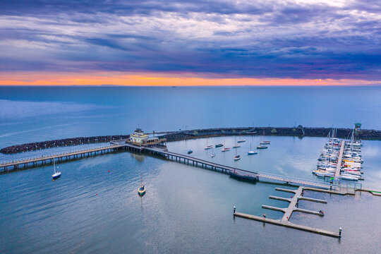 Aerial view of a coastal marina under a colourful sunset