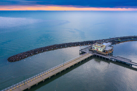 Aerial view of a pavilion on a jetty on a calm bay at sunset