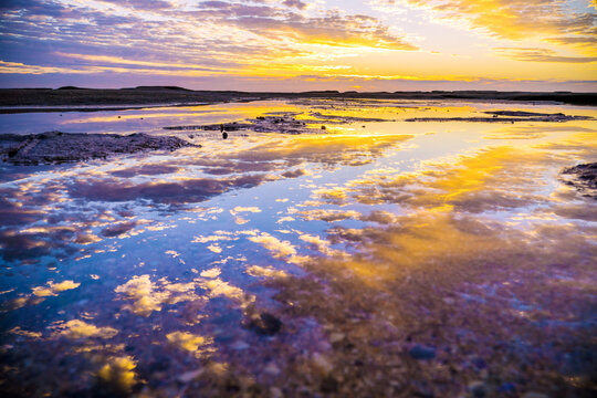 A colourful sunrise reflected in still rock pools