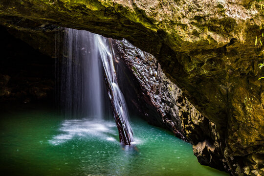 Water flowing through natural arch into underground cave