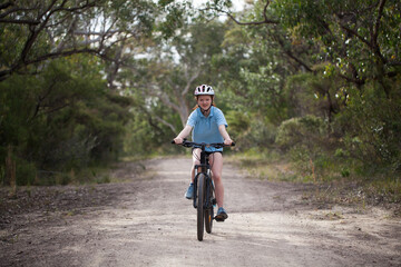 School girl riding a mountain bike on a bush trail