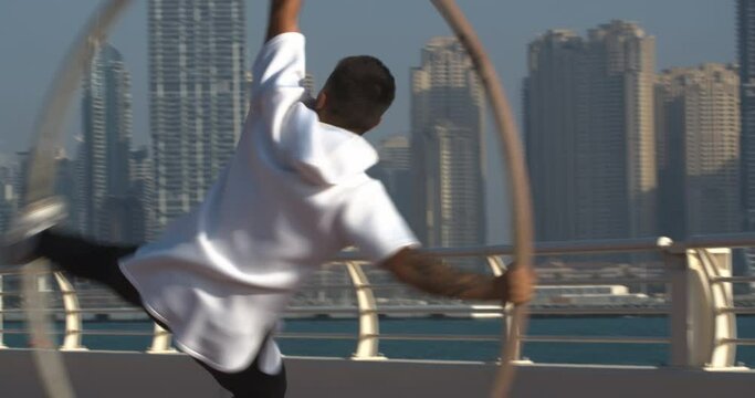 Athletic man is doing wheel gymnastics, spinning on high speed, Dubai, 4k