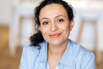 Female formal portrait. Close-up portrait of joyful successful elegant mixed race woman, business lady or assistant, dressed in formal shirt and glasses, looking at camera, smiling friendly