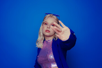 A girl in a blue jacket on a blue background in make-up in the style of the 70s, 80s, 90s covers...