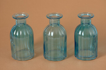 Three Blue Ribbed Glass Bottles Aligned on Warm Ochre Background