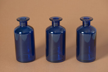 Three cobalt blue glass bottles stand in a row against a warm beige background. Their sleek, vintage-inspired form highlights simplicity and balance.