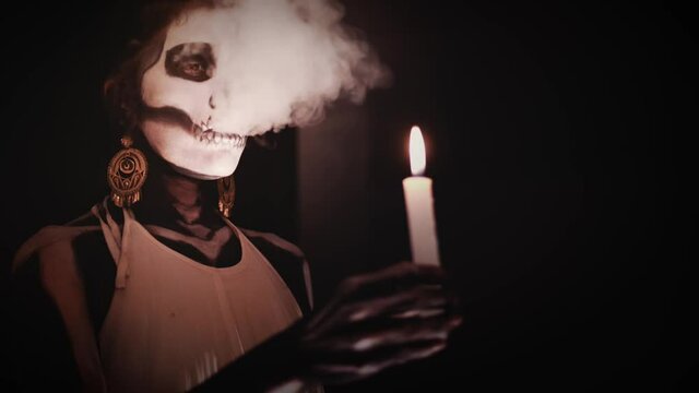 Hispanic woman in a performance with smoke and candles for the day of the death in Mexico. Body paint of a skeleton for a mexican celebration. Slow motion	