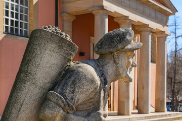 Sculpture of a winegrower carrying a back basket (Skulptur des Logel tragenden Winzers) in front of the church St. Ludwig in Bad Dürkheim, Germany