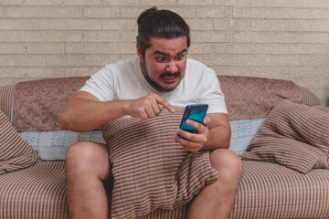 An angry and triggered man rants and scolds someone on videocall on the phone while sitting on the...