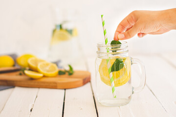 Woman prepares a lemon and mint drink. unfocused background