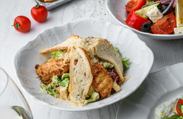 Fresh Chicken Caesar Salad with chicken breast, lettuce, tomatoes, parmesan, croutons on plate over light wooden background. Healthy food, clean eating, close up