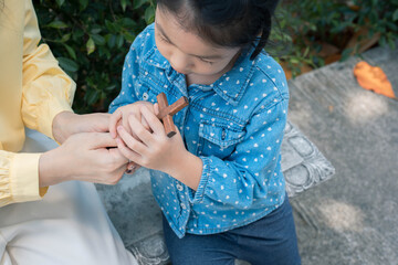 Asian woman praying with wooden cross outdoor.