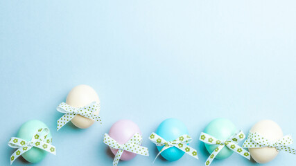 Easter flat. Colorful egg with tape ribbon on pastel blue background in Happy Easter decoration. Spring holiday top view concept.