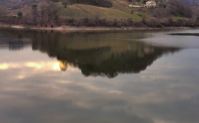 Verdi colline dell’Appennino marchigiano si riflettono al tramonto nelle acque del lago