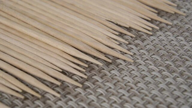 Sharpened wooden new toothpicks are stacked in a row on a braided kitchen napkin. Macro. Dolly Shot