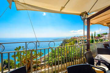 View from a hillside cafe's covered patio seating of the Mediterranean sea and coastline of Taormina, Italy, on the island of Sicily.