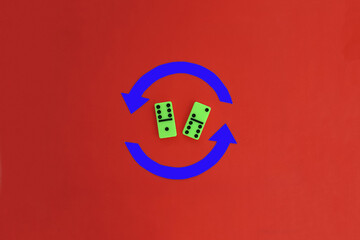 Two dominoes of green color, two arrows of blue color on a red background. The concept of random...