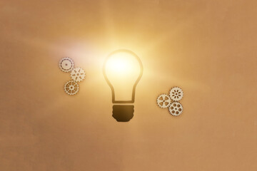 Electric light bulb, six wooden gears on a light brown background.  Creative ideas, joint business project.