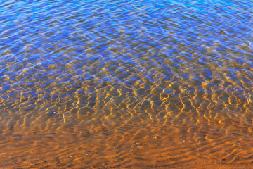 Ripples on the transparent river water . The bottom is visible through clear water