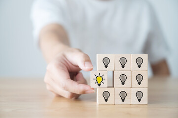 Conceptual of creative idea and innovation. Hand picked wooden cube block with light bulb icon