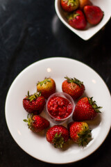 Overhead shot of a white plate with natural and fresh strawberries, very red