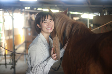 馬のブラッシングをする女性