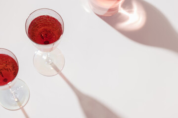 Two glasses of rose wine or champagne sweet and dry, top view and shadows from sun. Light alcohol sparkling drink for party.