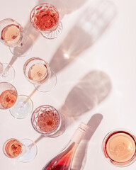 Fototapeta Many glasses of rose wine and bottle sparkling pink wine top view. Light alcohol drink for party. obraz