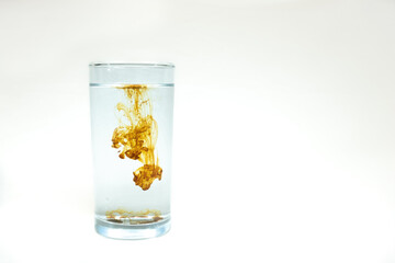 A single drop of concentrated Colloidal Silver being diluted in a glass of water. Room for text.