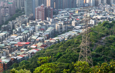Power lines and tower on forested hill with urban neighborhoods in the background - Taipei, Taiwan