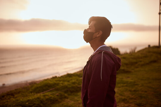 Hombre joven descansa en un parque durante un atardecer de verano.  Hombre mirando al horizonte del mar. 