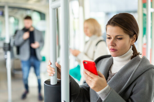 Positive woman reading from mobile phone screen in tram. High quality photo