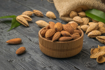 A bowl with peeled almonds on the background of unpeeled almonds spilling out of the bag.