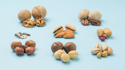 Peeled and unpeeled macadamia nuts on the background of various nuts.