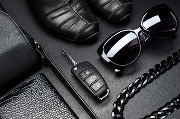 Woman accessories in business style, shoes, car key, jewelry and other luxury objects for businesswoman on leather black background, fashion industry, selective focus  - 423877085