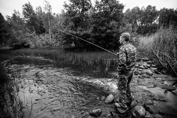 Fisherman catching fish on the lake. Black and white photo.