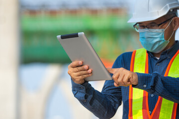 Asian man Senior Engineer expert professional use tablet work on site construction, Then man wera face mask protect coronavirus covid19 ,PM2.5