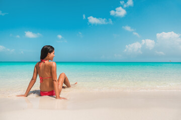 Beach travel Caribbean south vacation. Asian bikini woman relaxing sunbathing in water tanning enjoying sun. Winter holidays.