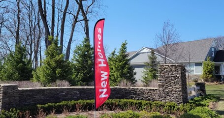 A new homes banner blows in the wind at the entrance to a suburban community development.