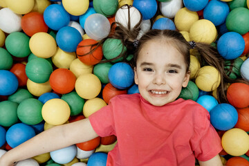 Fototapeta na wymiar a child in the children's playroom. The girl is having fun among the colorful balls. Dry Pool Party